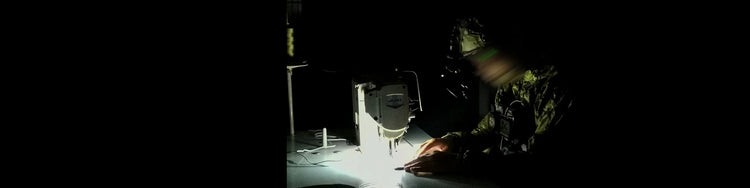 Tacvaults founder in QILO x SC Gen III AOR2 Windbreaker and PVS-14 monocular sewing on a JUKI in the dark.
